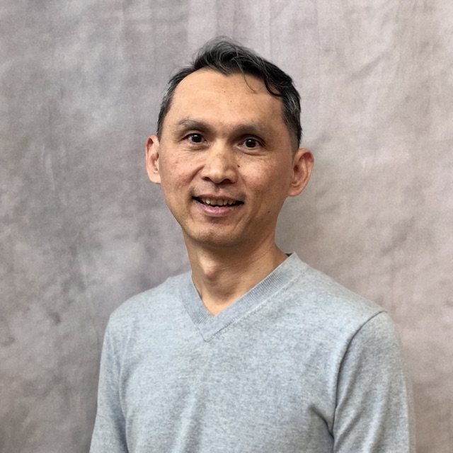 Headshot of Loc Lam smiling, wearing a light gray sweater